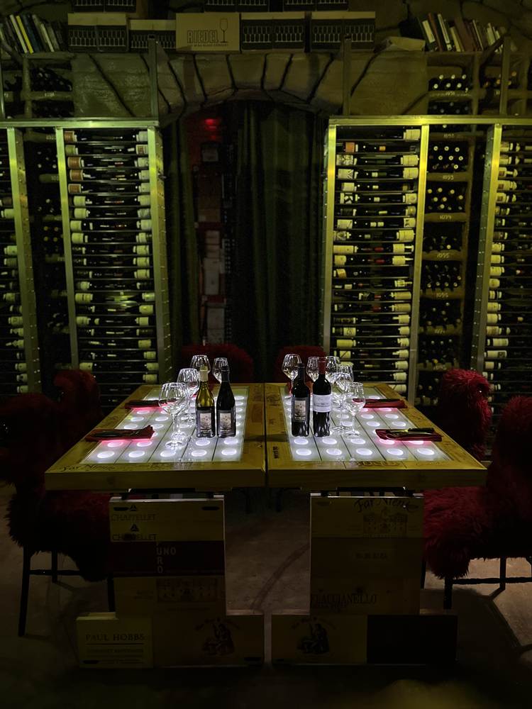A table with wine bottles and glasses

Description automatically generated