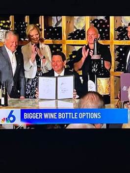 A group of people standing around a table with a menu Description automatically generated